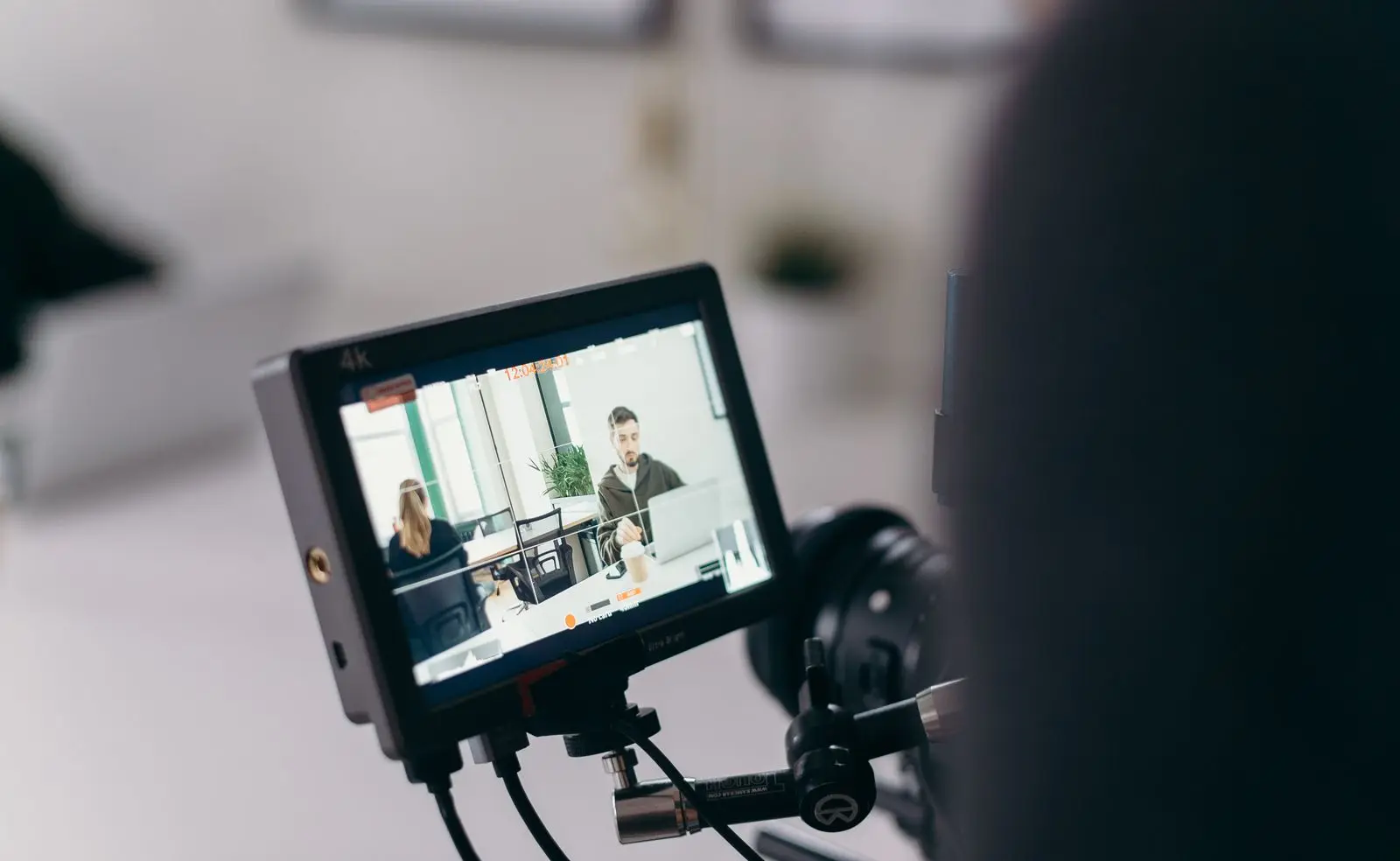 Het scherm van een videocamera toont een kantoor waarin een man aan zijn bureau wordt gefilmd