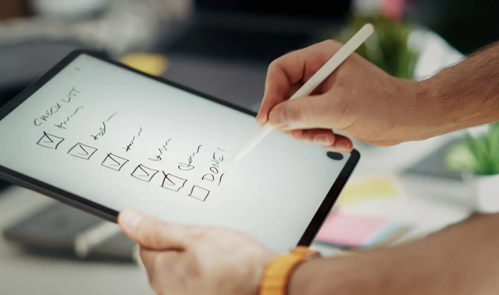 Handen vinken met een stylus taken af op een handgeschreven checklist op een tablet