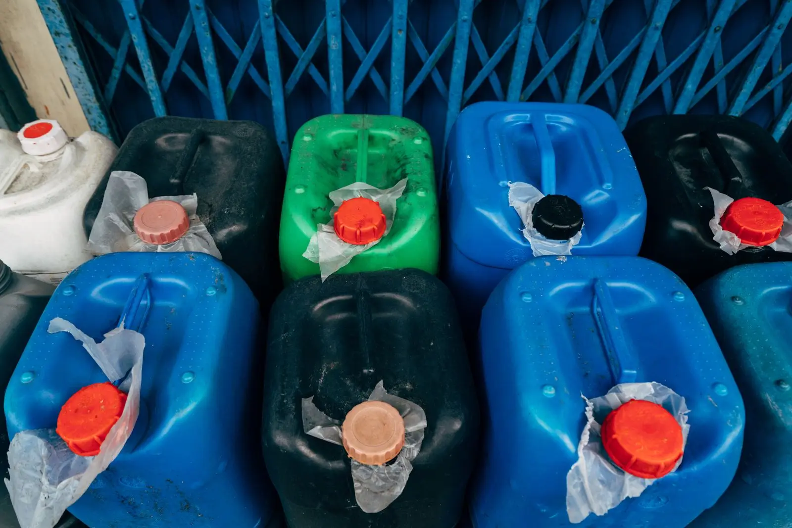 Blauwe, groene en zwarte jerrycans met gekleurde doppen, van bovenaf gezien